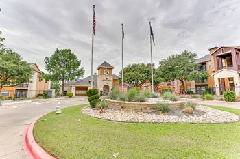 Property entrance with flagpoles and landscaped courtyard